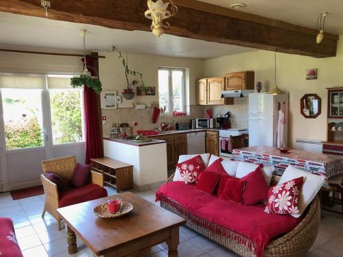 un salon avec un canapé rouge et une cuisine dans l'établissement Proche Mont St-Michel, deux maisons authentiques au cœur de la nature, domaine de l'Angevinière, à Saint-Laurent-de-Terregatte