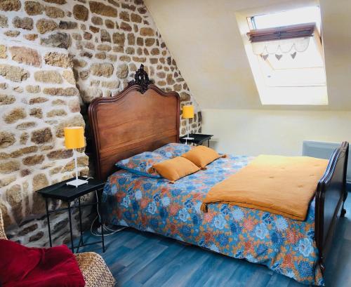 a bedroom with a bed and a stone wall at Domaine de l'Angevinière, 2 gîtes cosy, vue bocage proche Mont St-Michel in Saint-Laurent-de-Terregatte