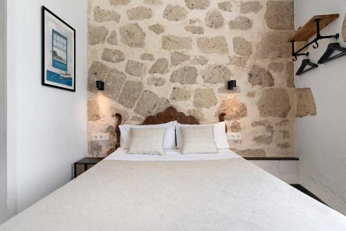 a bedroom with a large bed with a stone wall at Apto Azahara - Casa San Marcial in Las Palmas de Gran Canaria