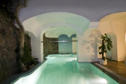 a swimming pool in a building with a tile floor at Hotel Villa Angelica in Ischia