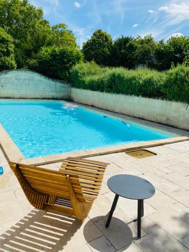 une chaise et une table à côté de la piscine dans l'établissement L'écrin de verdure, à Ligré