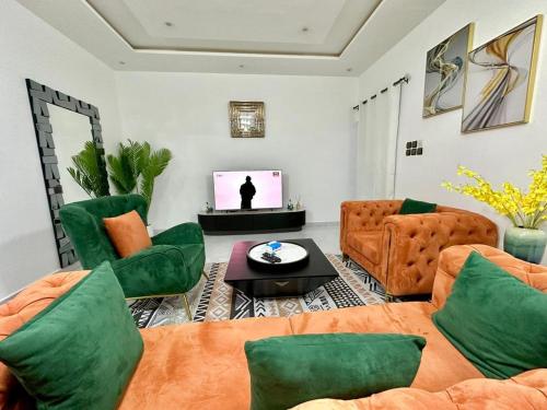 a living room with green furniture and a television at Luxe club des rois in Cotonou