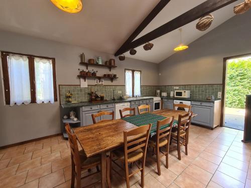 une grande cuisine avec une table et des chaises en bois dans l'établissement Maison paisible avec jardin clos, terrasse, proche lac d'Eguzon et villages médiévaux - FR-1-591-102, à Vigoux