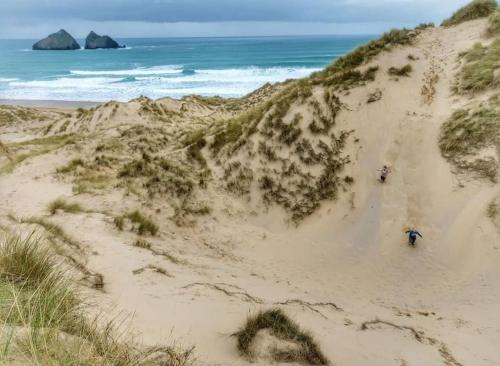 two people walking on a sandy beach near the ocean at Heart of Kernow Holidays in Bugle