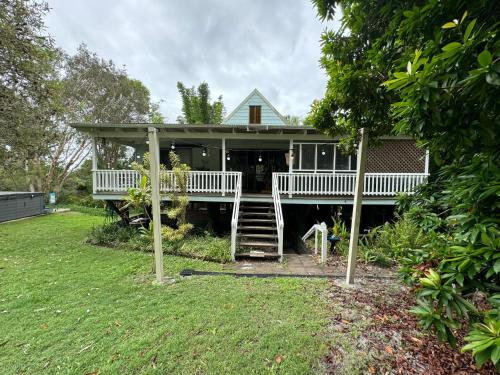 Una casa grande con porche y escaleras. en Coconut Cottage Bush Retreat- Pet Friendly, en Tin Can Bay