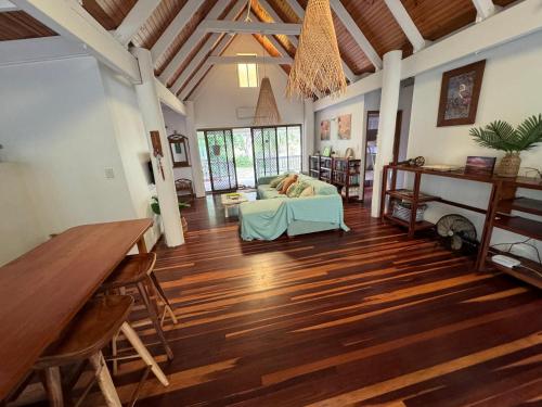 sala de estar con sofá y suelo de madera en Coconut Cottage Bush Retreat- Pet Friendly, en Tin Can Bay