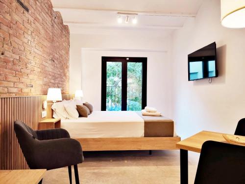 ARIQUS Fira Apartments في لوسبيتاليت دي يوبريغات: غرفة نوم بسرير وجدار من الطوب