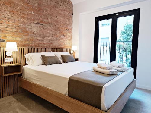 ARIQUS Fira Apartments في لوسبيتاليت دي يوبريغات: غرفة نوم بسرير كبير وبجدار من الطوب