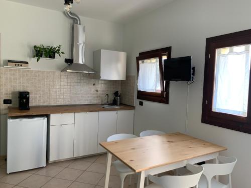 een keuken met een houten tafel en witte kasten bij angolo del cuore, relax e stile, app. indipendente in Casa Calari