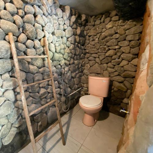 a bathroom with aige toilet and a stone wall at PALEO Stone Age in Karangwetan