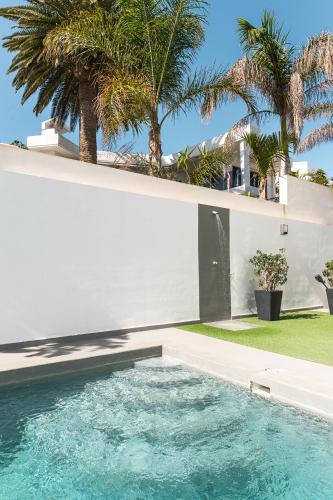a swimming pool in front of a house with palm trees at Chalet con piscina en Tabaiba by Alterhome in Santa Cruz de Tenerife