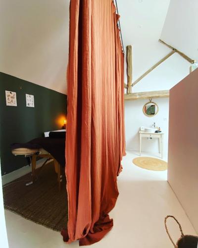- un salon avec un rideau orange dans l'établissement L'écrin de verdure, à Ligré