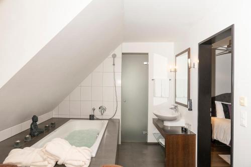 a bathroom with a bath tub and a sink at Boutique Hotel Weisses Kreuz - Adult only Hotel in Luzern