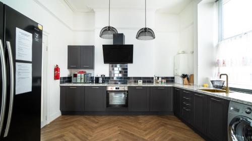 a kitchen with black and white cabinets and appliances at Plymouth Hoe - Beautiful 5 Bedroom Victorian House - Central Location in Plymouth