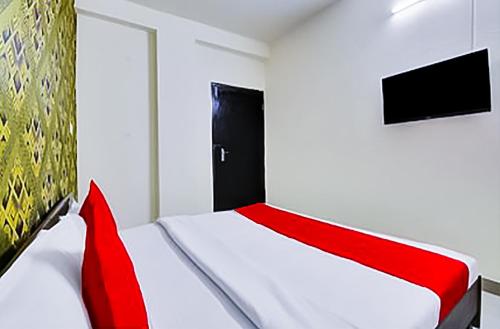 a bedroom with a red and white bed and a television at Hotel In Lajpat Nagar in New Delhi
