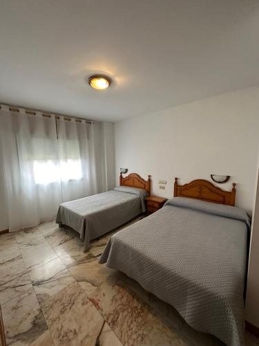 a bedroom with two beds and a tile floor at P Residencia PIVIDAL in Picaraña