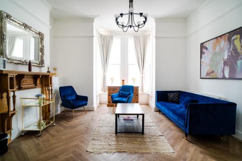 a living room with a blue couch and two blue chairs at Plymouth Hoe - Beautiful 5 Bedroom Victorian House - Central Location in Plymouth