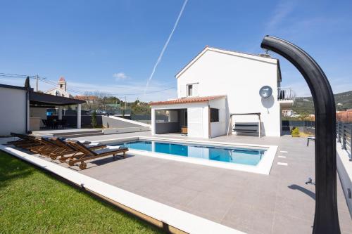 a backyard with a swimming pool and a house at Villa Stone - Pool house 100 meters from the beach in Vinišće
