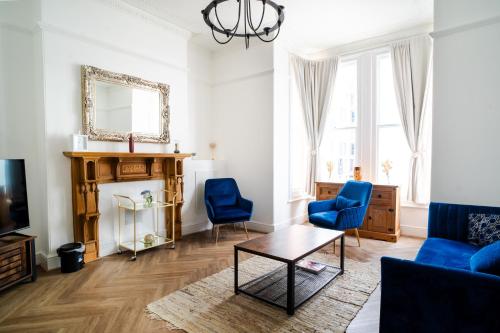 a living room with blue chairs and a table at Plymouth Hoe - Beautiful 5 Bedroom Victorian House - Central Location in Plymouth