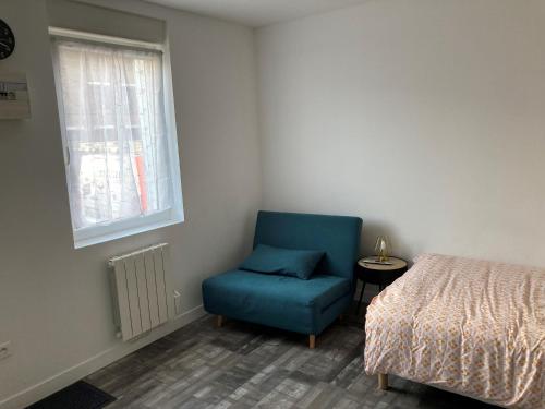 - une chambre avec une chaise bleue à côté d'un lit dans l'établissement Studio indépendant, à Raismes