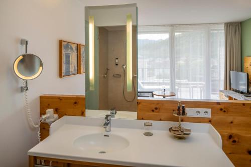 ein Bad mit einem Waschbecken und einem Spiegel in der Unterkunft Villa Seilern Vital Resort in Bad Ischl