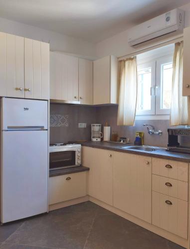 a kitchen with white cabinets and a white refrigerator at Avissalou Apartments in Agios Romanos