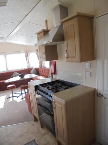 a kitchen with a stove and a living room at Seaview Ingoldmells Bromley 10 Berth 4 Bedrooms FREE WIFI in Ingoldmells