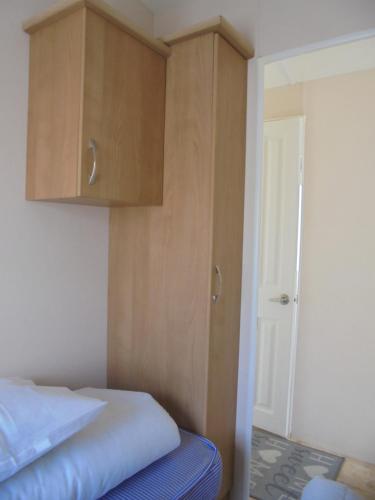 a bedroom with a bed and wooden cabinets at Seaview Ingoldmells Bromley 10 Berth 4 Bedrooms FREE WIFI in Ingoldmells
