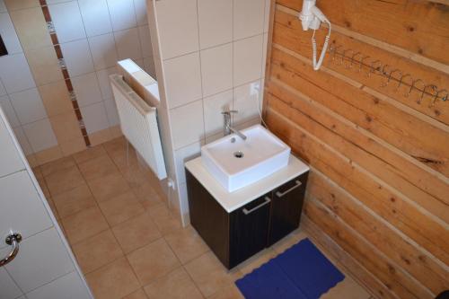 a bathroom with a white sink and a wooden wall at Chalupa Pohoda Slovenský raj Hrabušice in Hrabušice