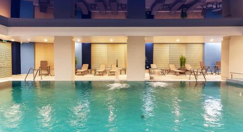 una piscina en un hotel con sillas y mesas en Motlawa Riverview Apartment OIdtown, en Gdansk