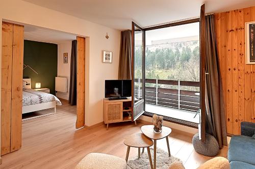un salon avec un canapé, une télévision et une fenêtre dans l'établissement Moho des Oursons - Pistes de ski à 450m, à La Bresse