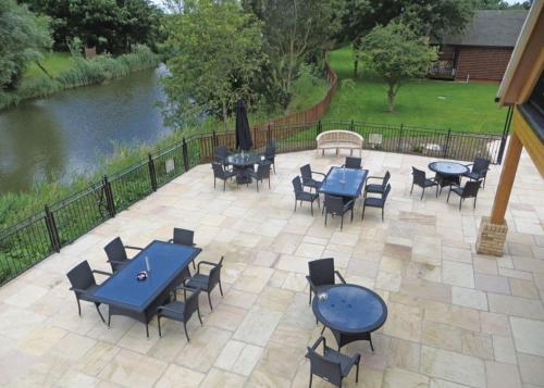 a patio with blue tables and chairs next to a river at Old Nene Golf And Country Club in Upwood