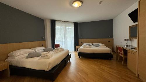 a bedroom with two beds and a kitchen with a window at Hotel Oasi Wellness & Spa in Riva del Garda