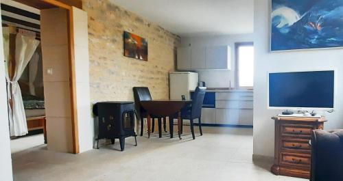 une cuisine avec une table et des chaises et une télévision dans l'établissement Petite maison d'art et d'hôtes, à Leuglay