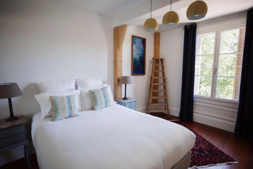 una camera da letto con letto bianco con cuscini e scala di Demeure du Haut Canteloup a Honfleur
