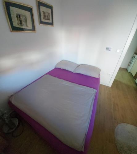 een bed met paarse en witte lakens in een kamer bij Apartman Elit in Kragujevac