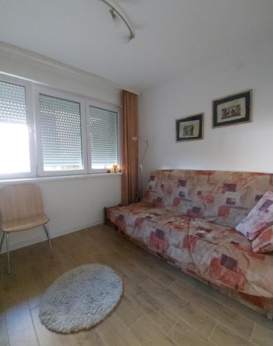 een slaapkamer met een bed, een stoel en ramen bij Apartman Elit in Kragujevac
