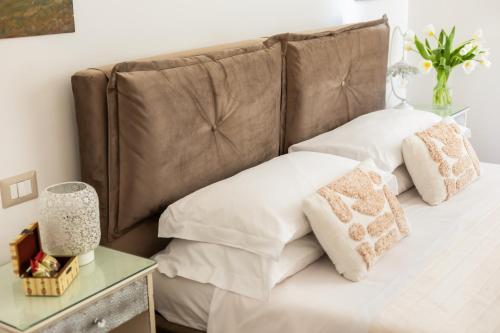 a bed with white pillows and a brown headboard at Guest House Maison 6 in Lido di Ostia