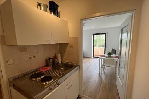 uma cozinha com um fogão, um lavatório e uma mesa em Schönes Apartment mit Balkon in Mannheim Nahe Rheinauer See em Mannheim