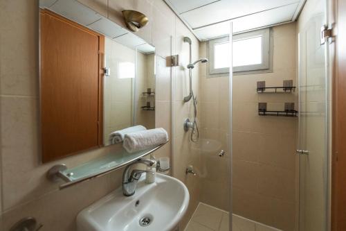 ein Bad mit einem Waschbecken und einer Dusche mit einem Spiegel in der Unterkunft 2BD and 2 Bath duplex on the Hilton beach in Tel Aviv