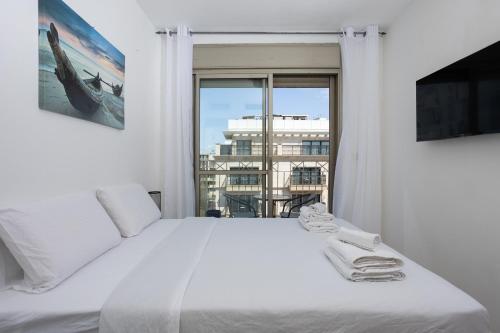 ein Schlafzimmer mit einem großen weißen Bett und einem Fenster in der Unterkunft 2BD and 2 Bath duplex on the Hilton beach in Tel Aviv