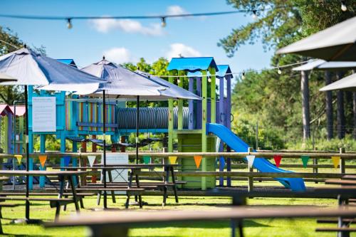 a playground with tables and chairs and umbrellas at Beaulieu Hotel in Lyndhurst