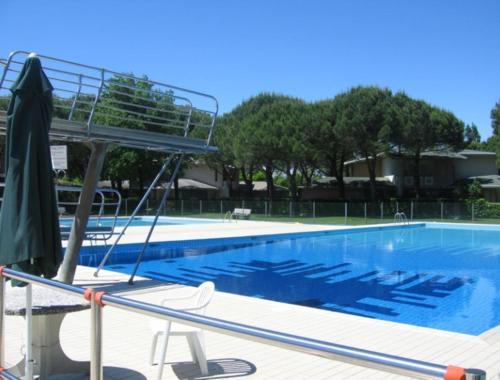 ein Pool mit Sonnenschirm und Stühlen daneben in der Unterkunft Comfy studio in a residence with pool - Beahost in Bibione
