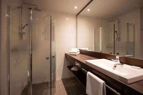 y baño con lavabo y ducha. en Hampshire Hotel - Delft Centre, en Delft