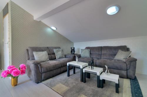 a living room with two couches and tables and pink flowers at Casa Memory in Crikvenica