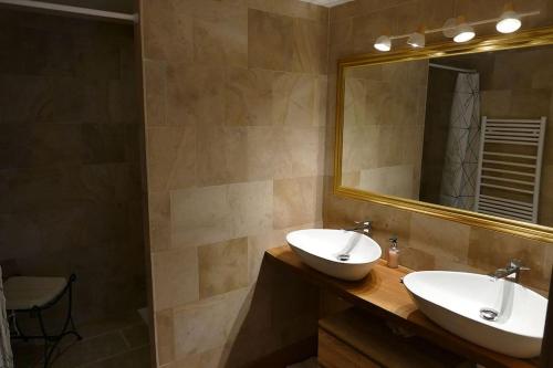 a bathroom with two sinks and a large mirror at La maison d'art et d'hôtes in Leuglay