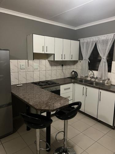 eine Küche mit weißen Schränken und einer Granitarbeitsplatte in der Unterkunft Proventures Self-catering House in Ondangwa