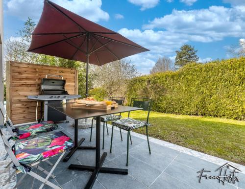 a picnic table with an umbrella on a patio at Magny's Oasis - DisneyLand 5min - Private Parking - Terrace & Garden in Magny-le-Hongre