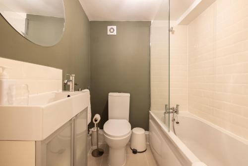 a bathroom with a toilet and a sink and a tub at The Brockwell Park Place - Bright 2BDR Flat in London