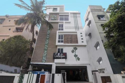 a white building with a palm tree in front of it at Super OYO Collection O RCC Pristine in Hyderabad